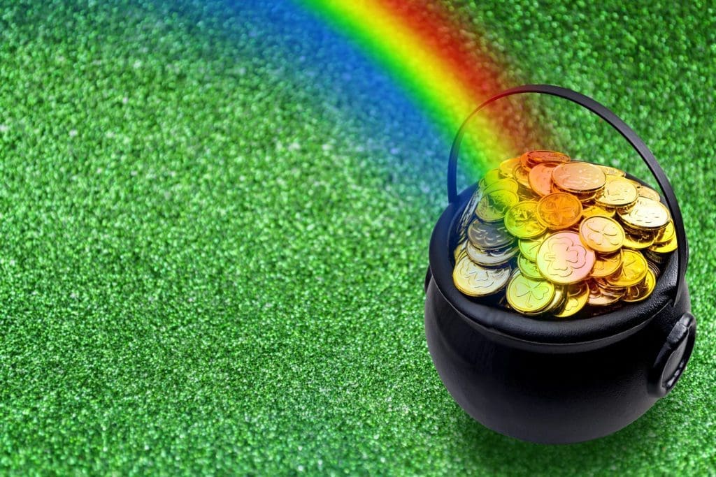 St Patricks Day pot of gold coins and rainbow on green grass